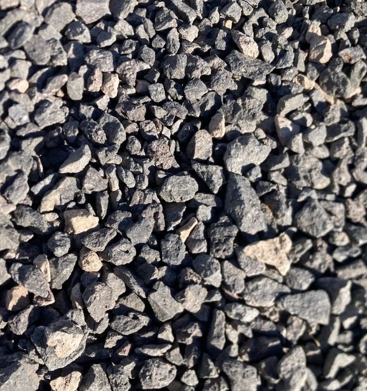 Close-up of dark gray crushed gravel stones, rough texture for driveways, landscaping and construction aggregate.