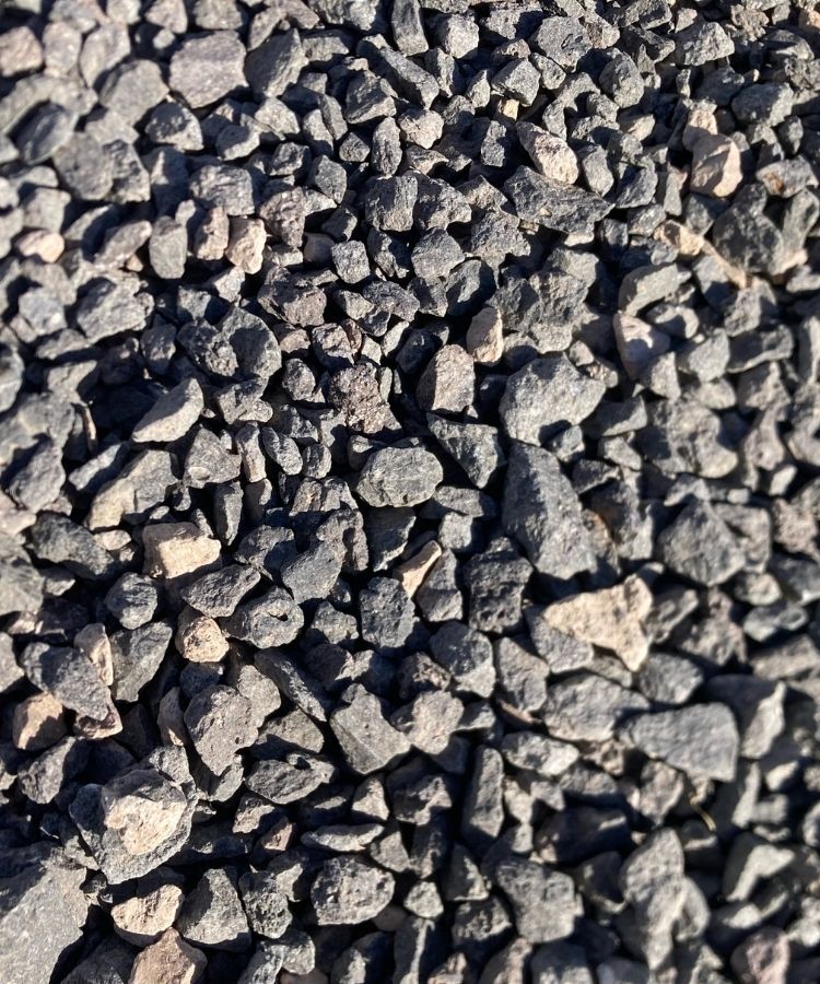 Close-up of dark gray crushed gravel stones, rough texture for driveways, landscaping and construction aggregate.
