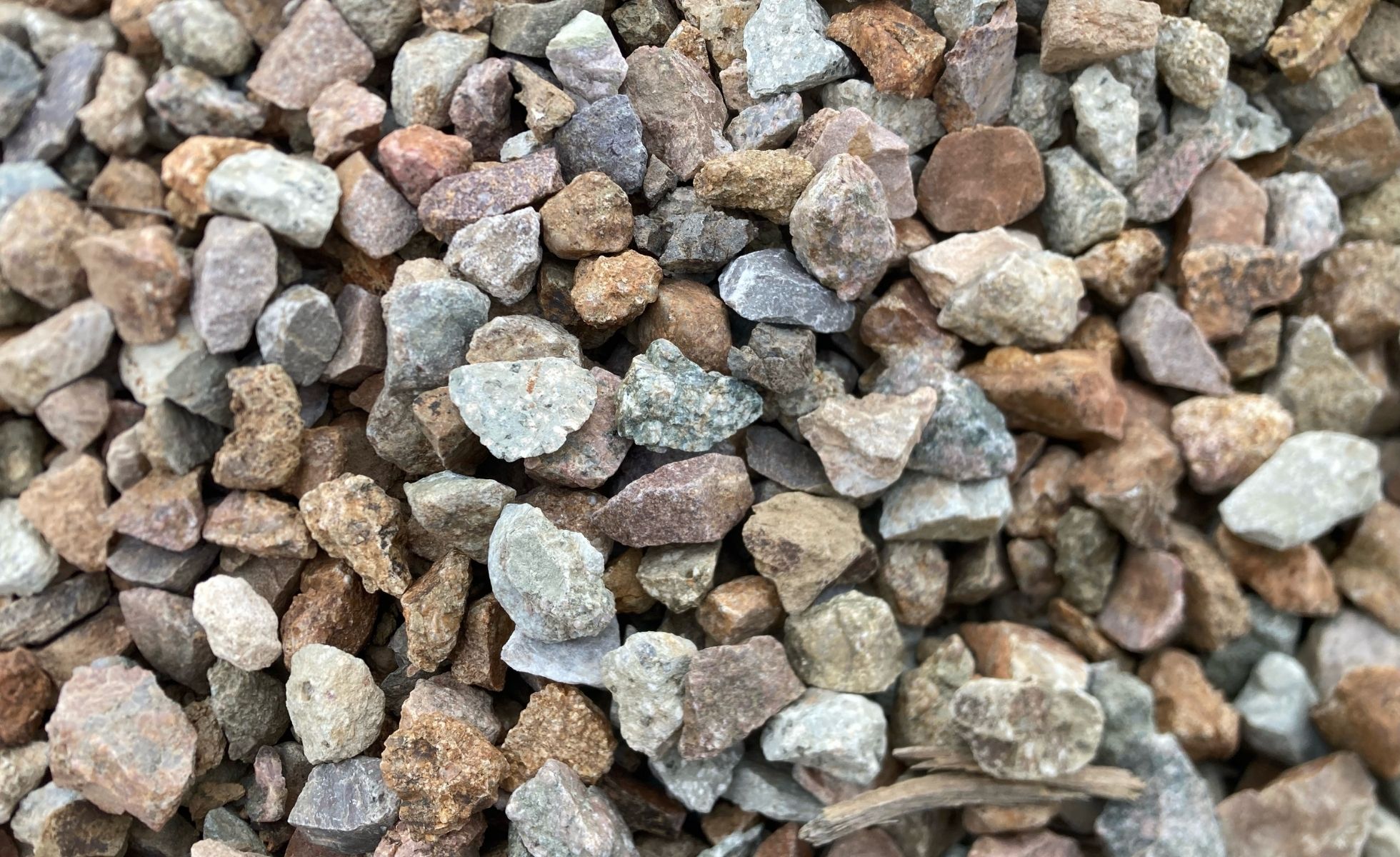 Close-up of mixed crushed stone gravel aggregate in brown and gray tones for landscaping, paths, and driveways.