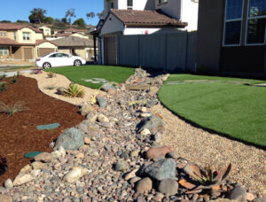 Xeriscape drought-tolerant front yard with dry riverbed, succulents and artificial turf at suburban home