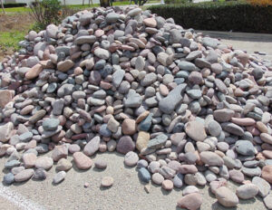 Pile of multicolored river rocks for landscaping, smooth decorative pebbles stacked outdoors on gravel