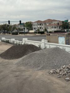 Gravel piles at roadside construction site near intersection with apartments and traffic lights in suburban neighborhood