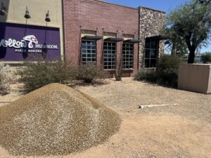 Mellow Mushroom Pizza Bakers exterior with gravel pile and desert landscaping under blue sky.