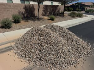 Curbside pile of decorative landscape gravel for desert xeriscape installation in a suburban neighborhood.