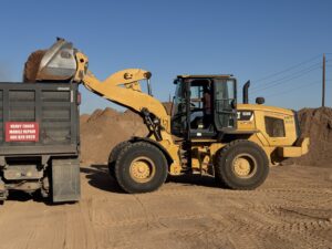 Caterpillar 938K wheel loader dumping dirt into a dump truck at an earthmoving construction site